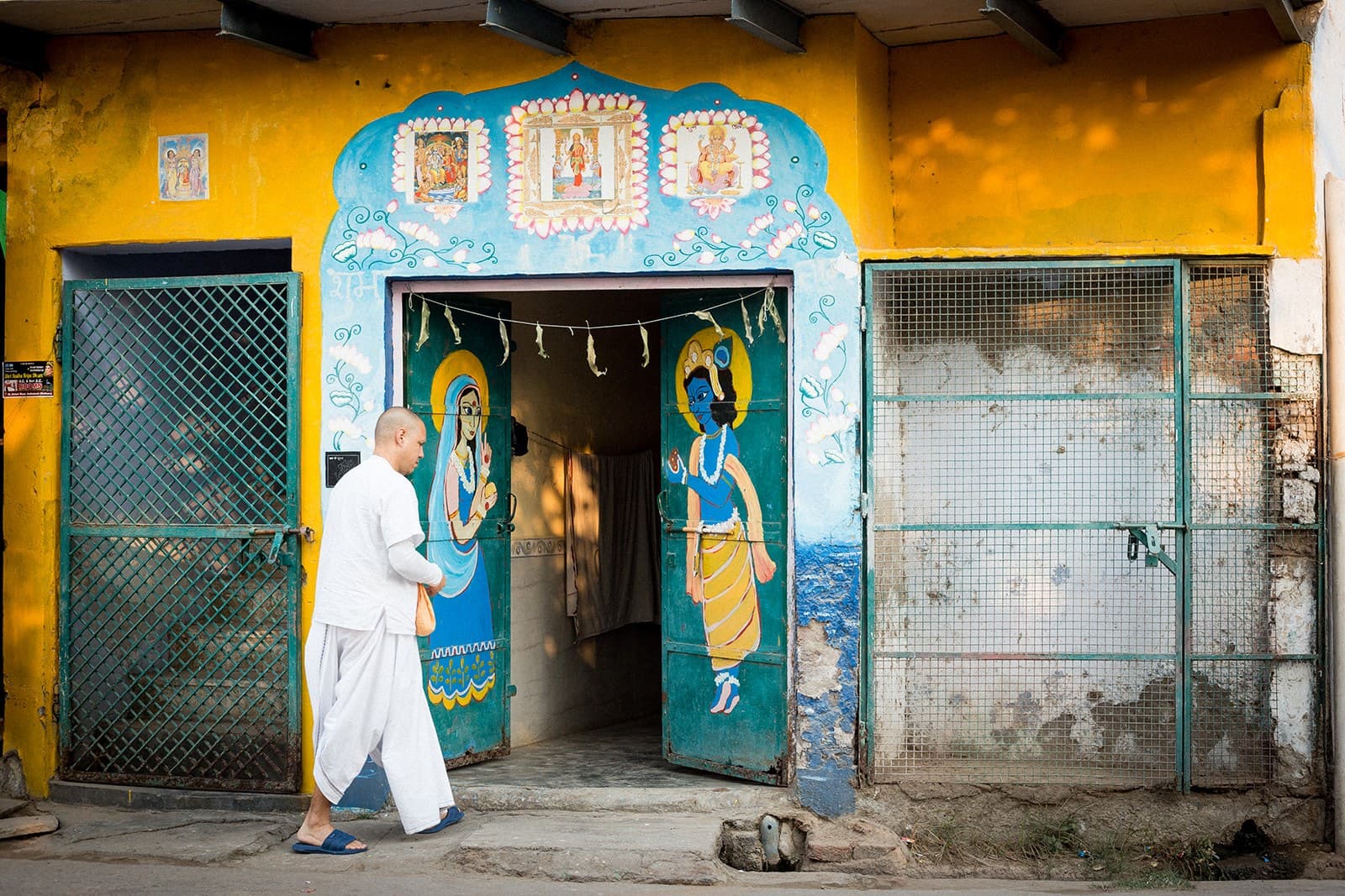 Devoto entrando por una puerta pintada con imágenes de Krishna